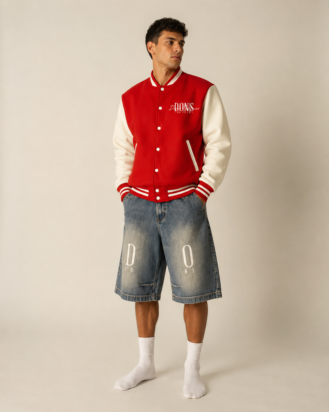 Person wearing a red and white varsity jacket with denim shorts on a plain background