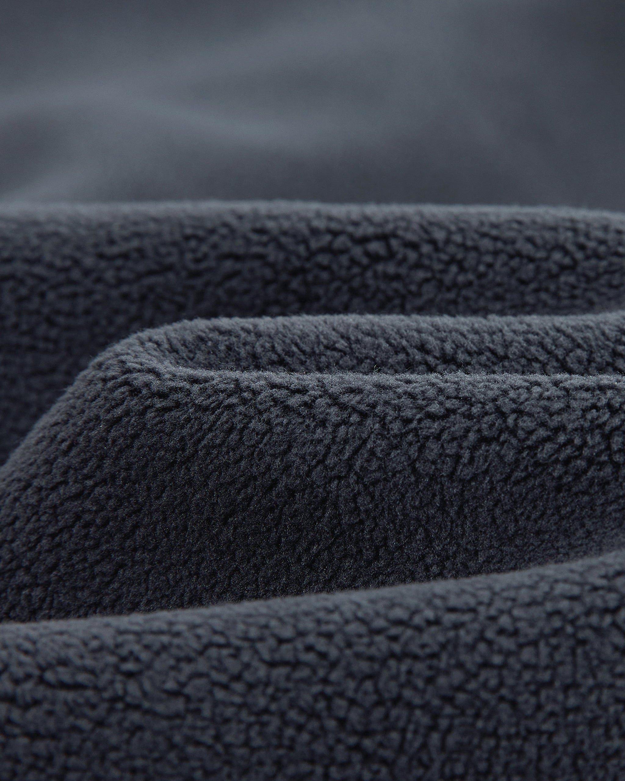 Close-up of dark gray fleece fabric with a textured surface.