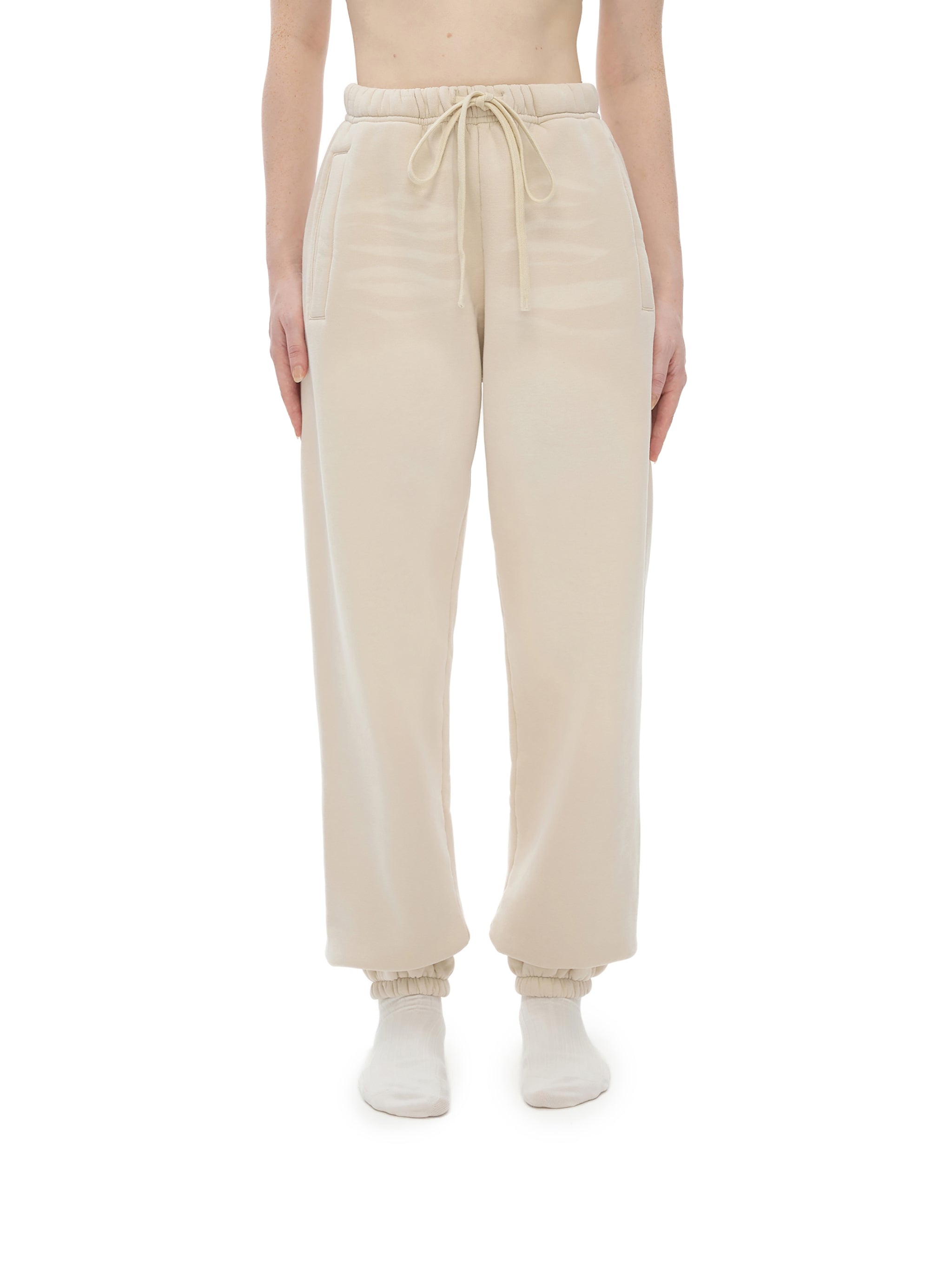 Beige sweatpants worn by a person on a white background