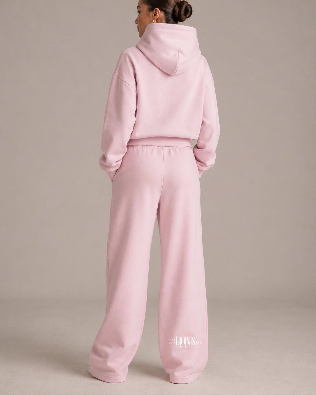 Person wearing a pink tracksuit with a plain background