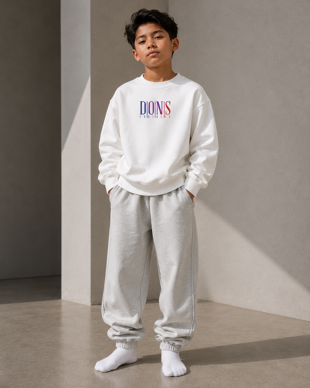 Person wearing a white sweatshirt with colorful text and gray pants against a neutral background