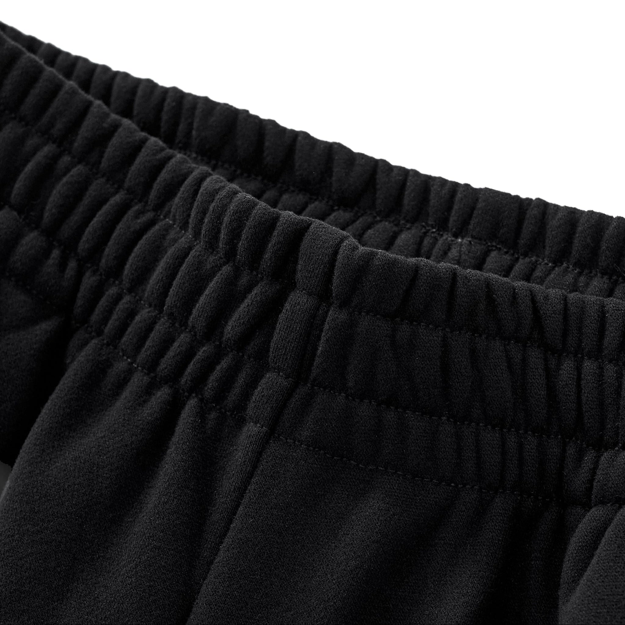 Close-up of black pants with an elastic waistband on a white background