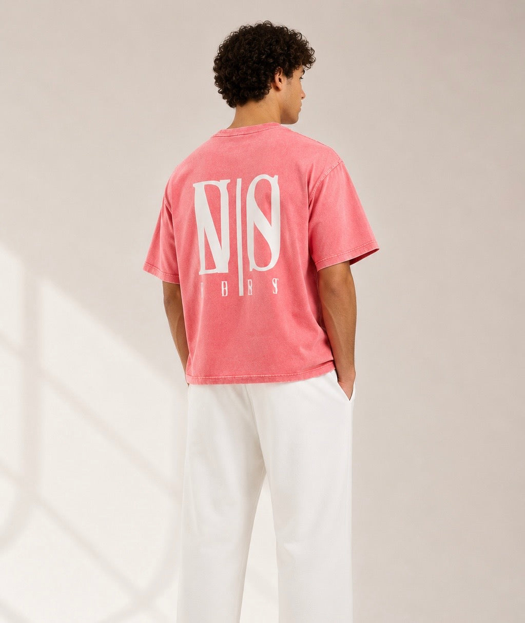Person wearing a pink t-shirt with a logo on the back against a neutral background