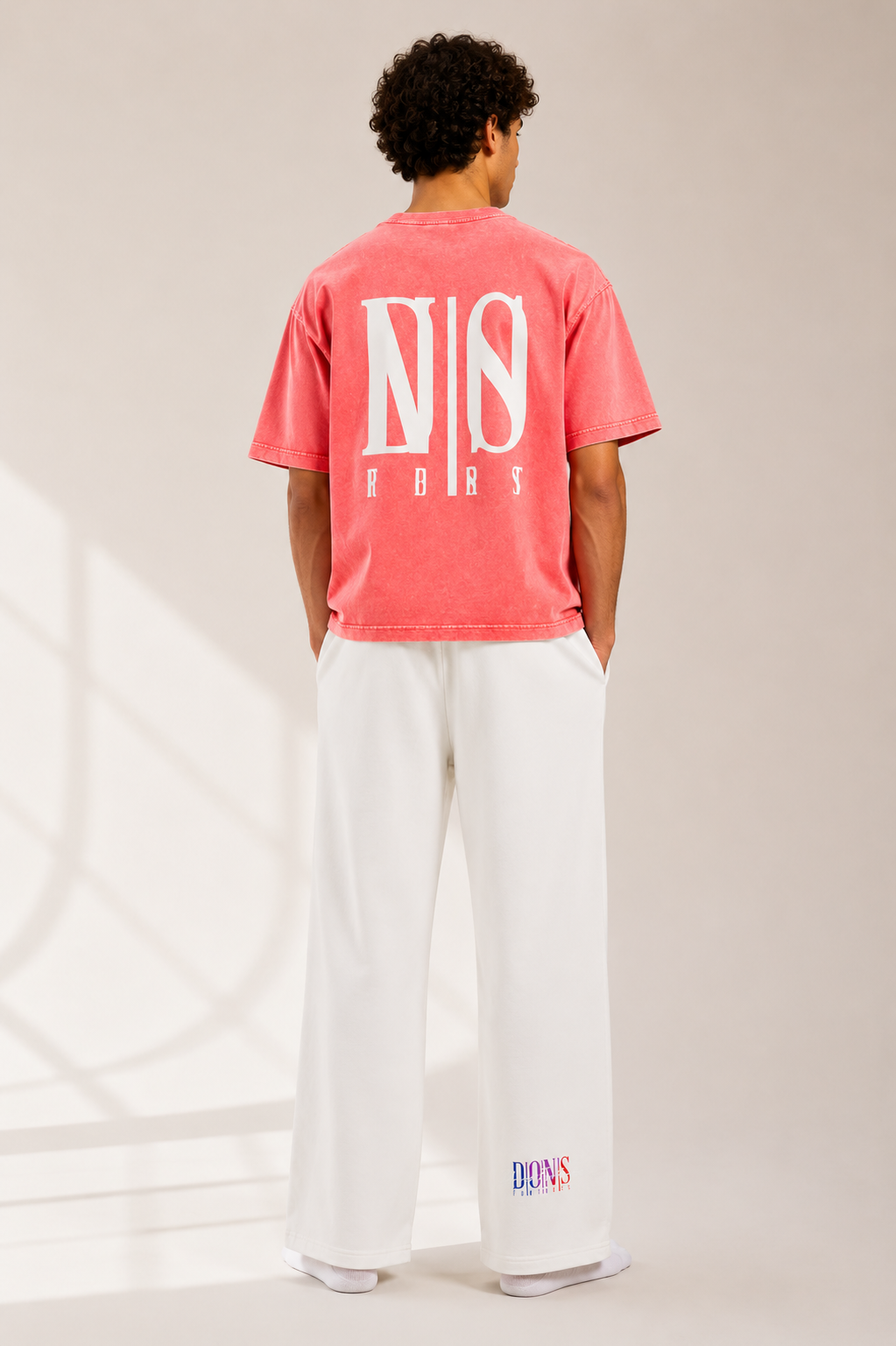 Person wearing a pink t-shirt with branding on the back, standing against a neutral background.