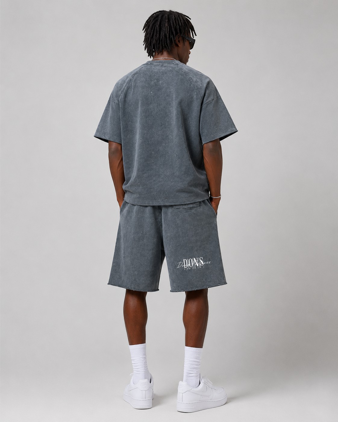 Person wearing a gray t-shirt and shorts set with branding on a plain background