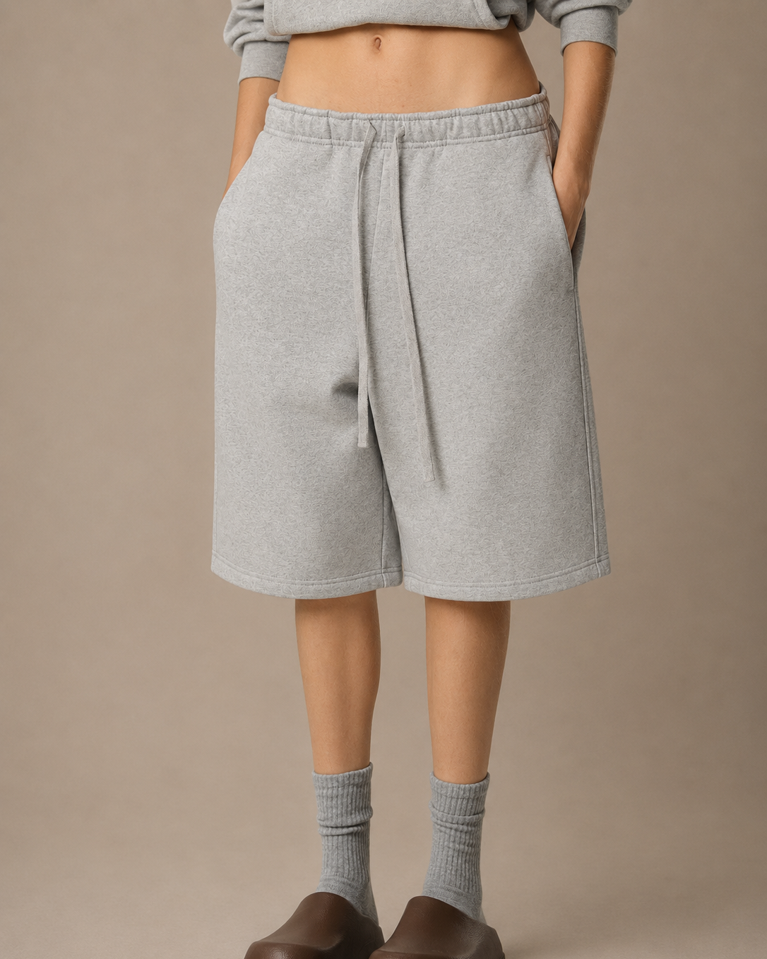 Person wearing gray shorts on a beige background
