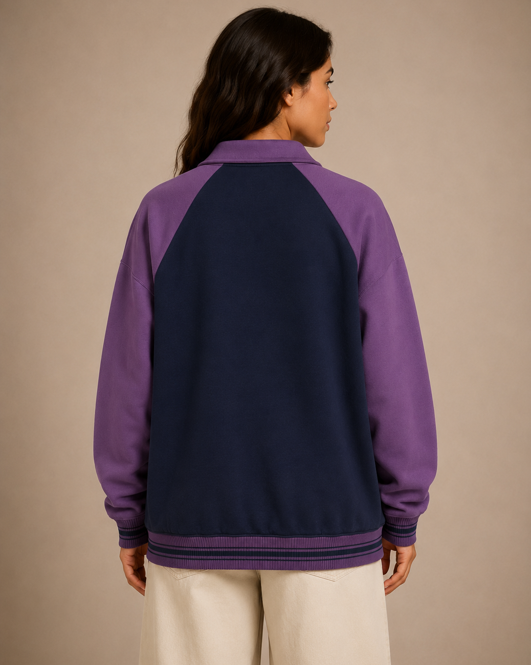 Person wearing a purple and navy color-blocked jacket on a beige background