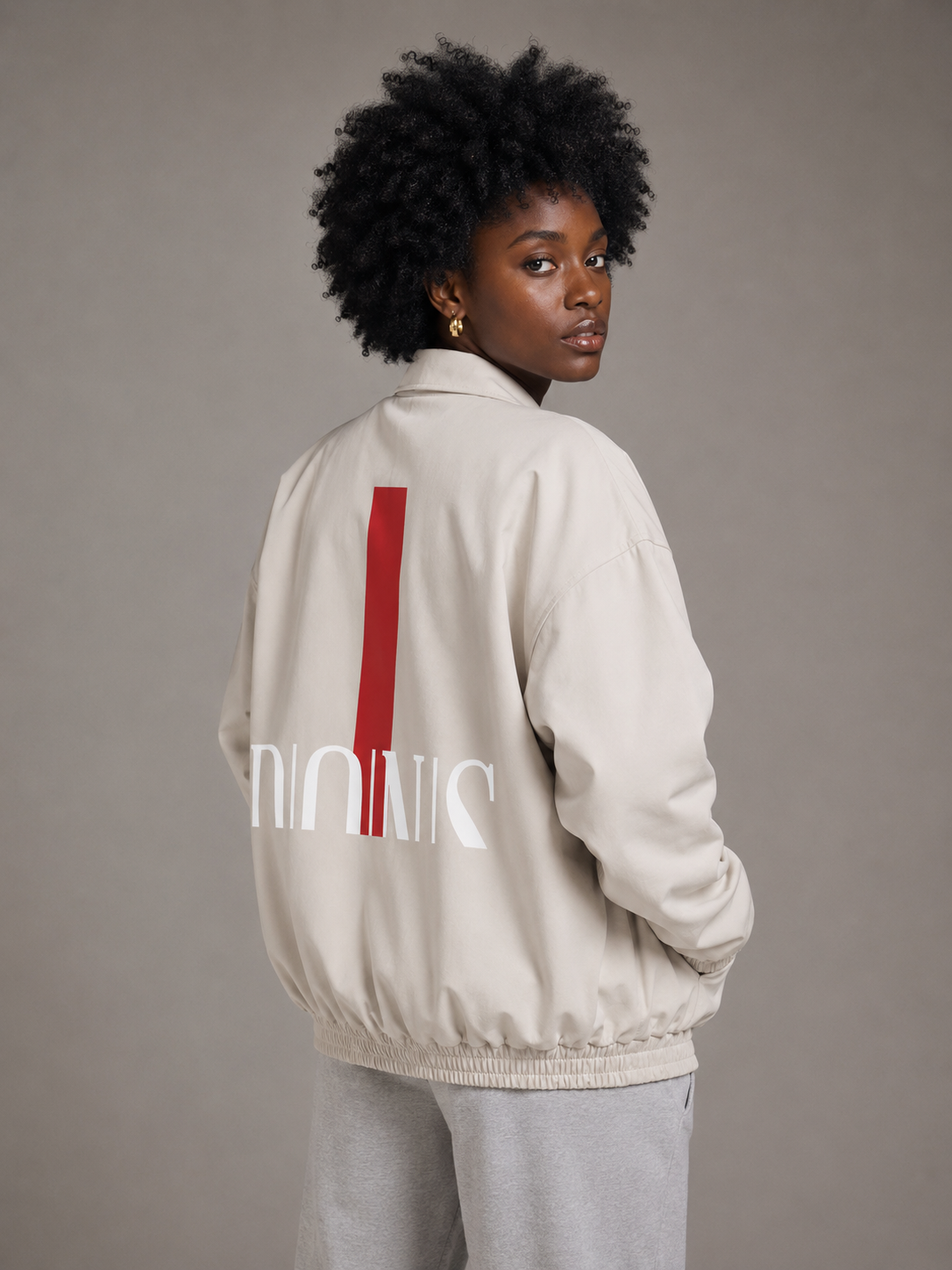 Person wearing a beige jacket with a red stripe and white text on a gray background