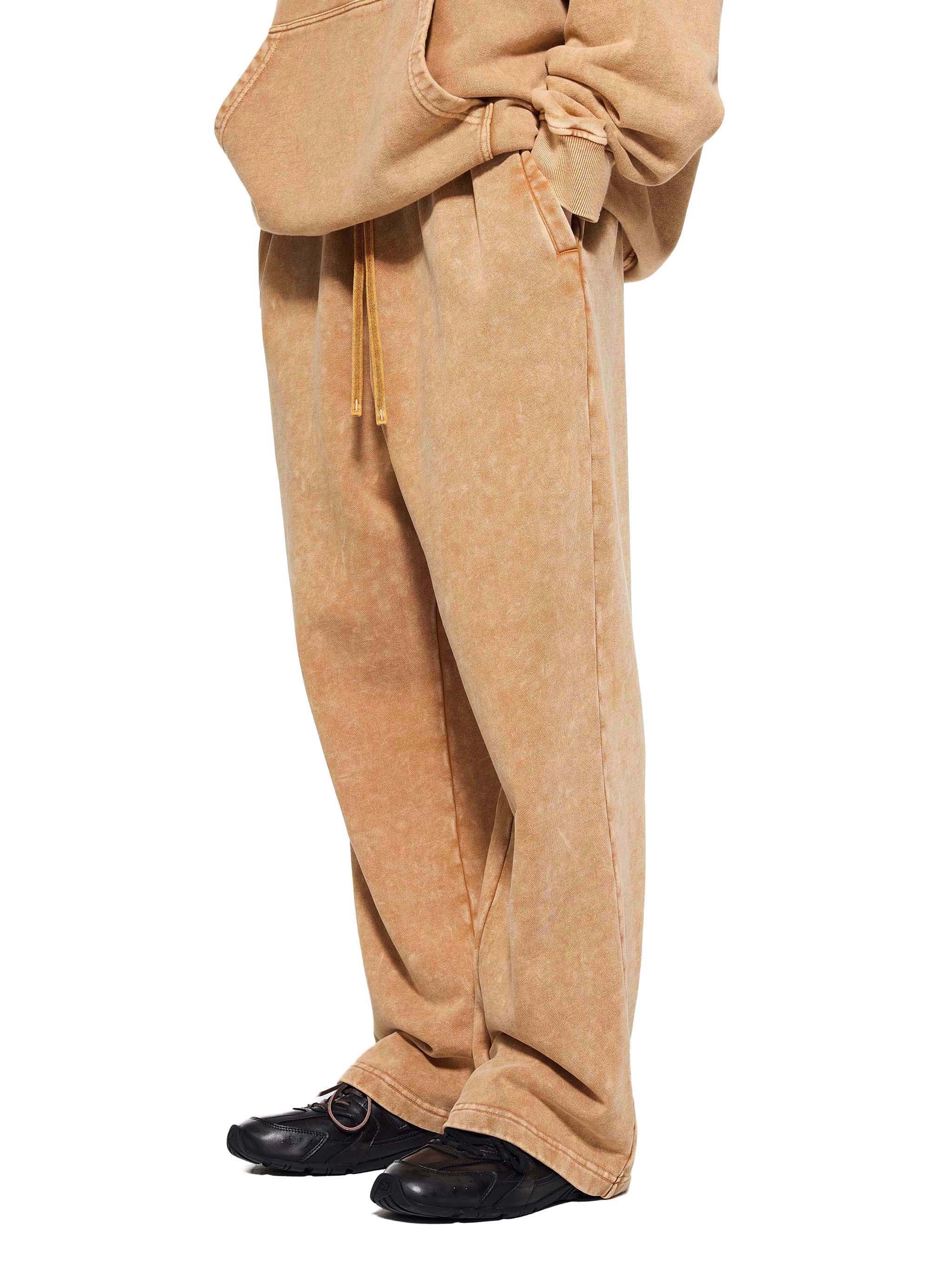 Tan hoodie and pants with black shoes on a white background