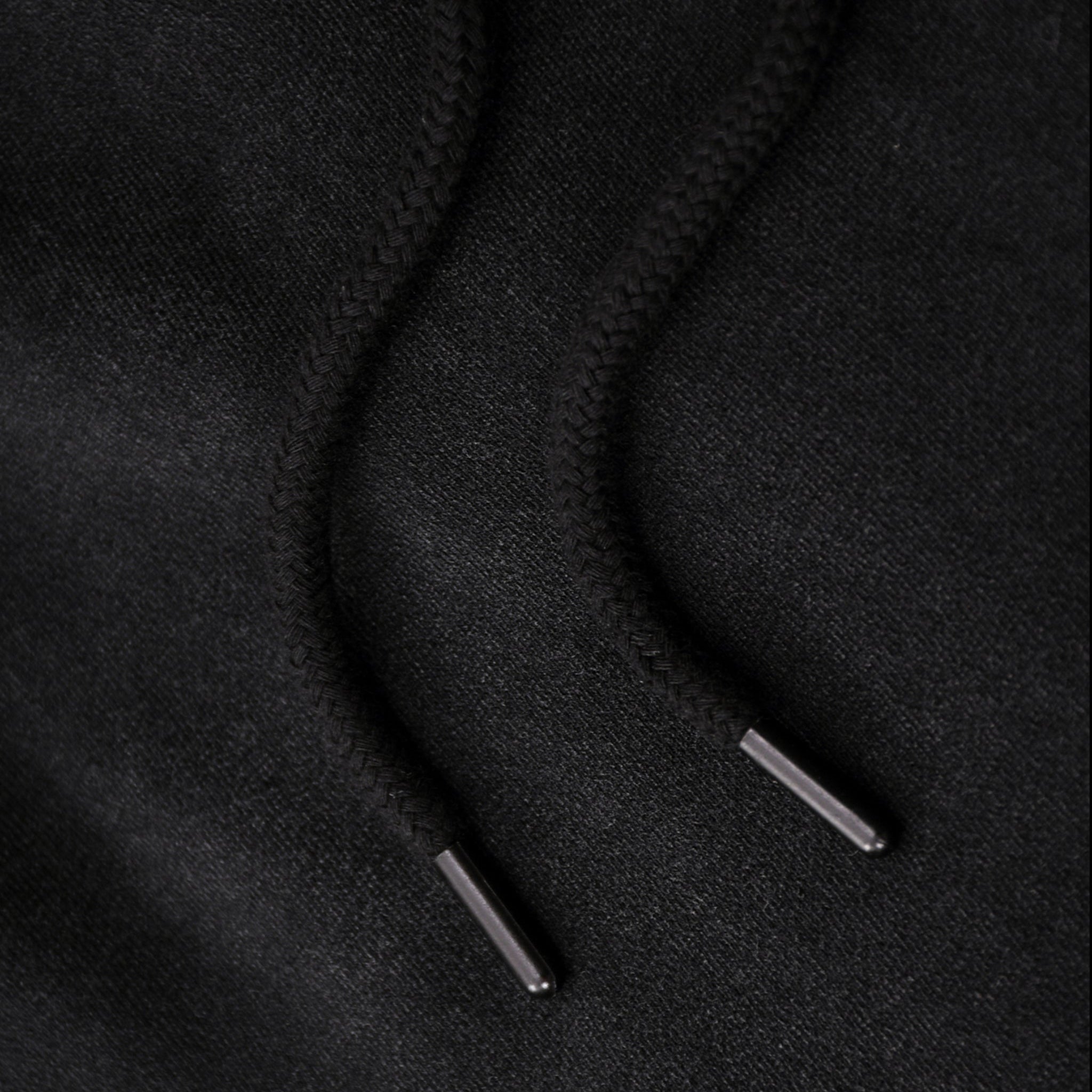 Close-up of black hoodie strings on a black background