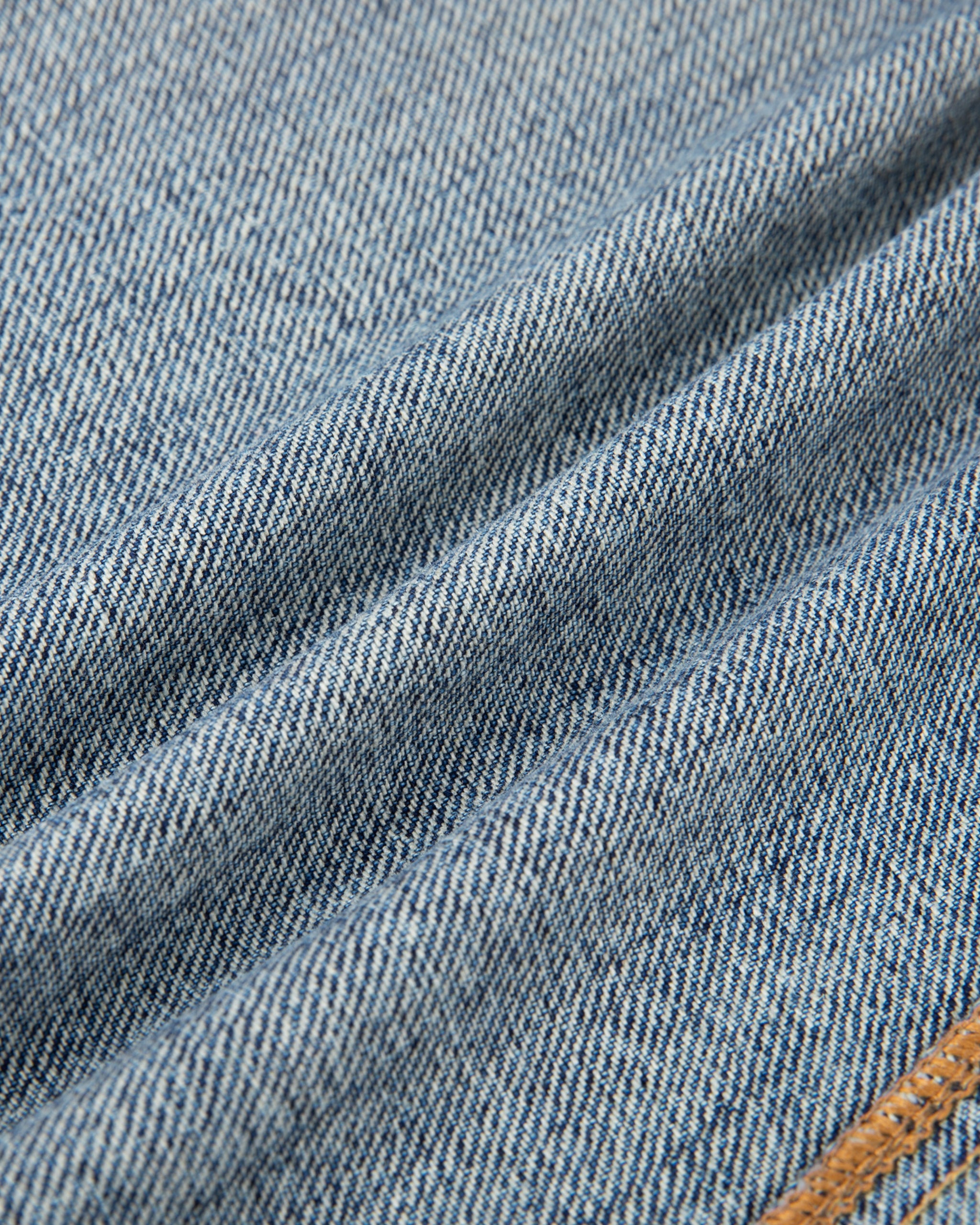 Close-up of blue denim fabric with a brown stitch detail