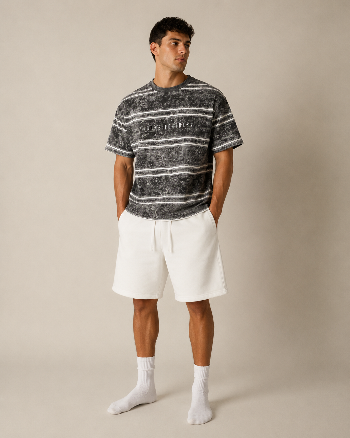 Man wearing a black and white striped t-shirt and white shorts on a beige background