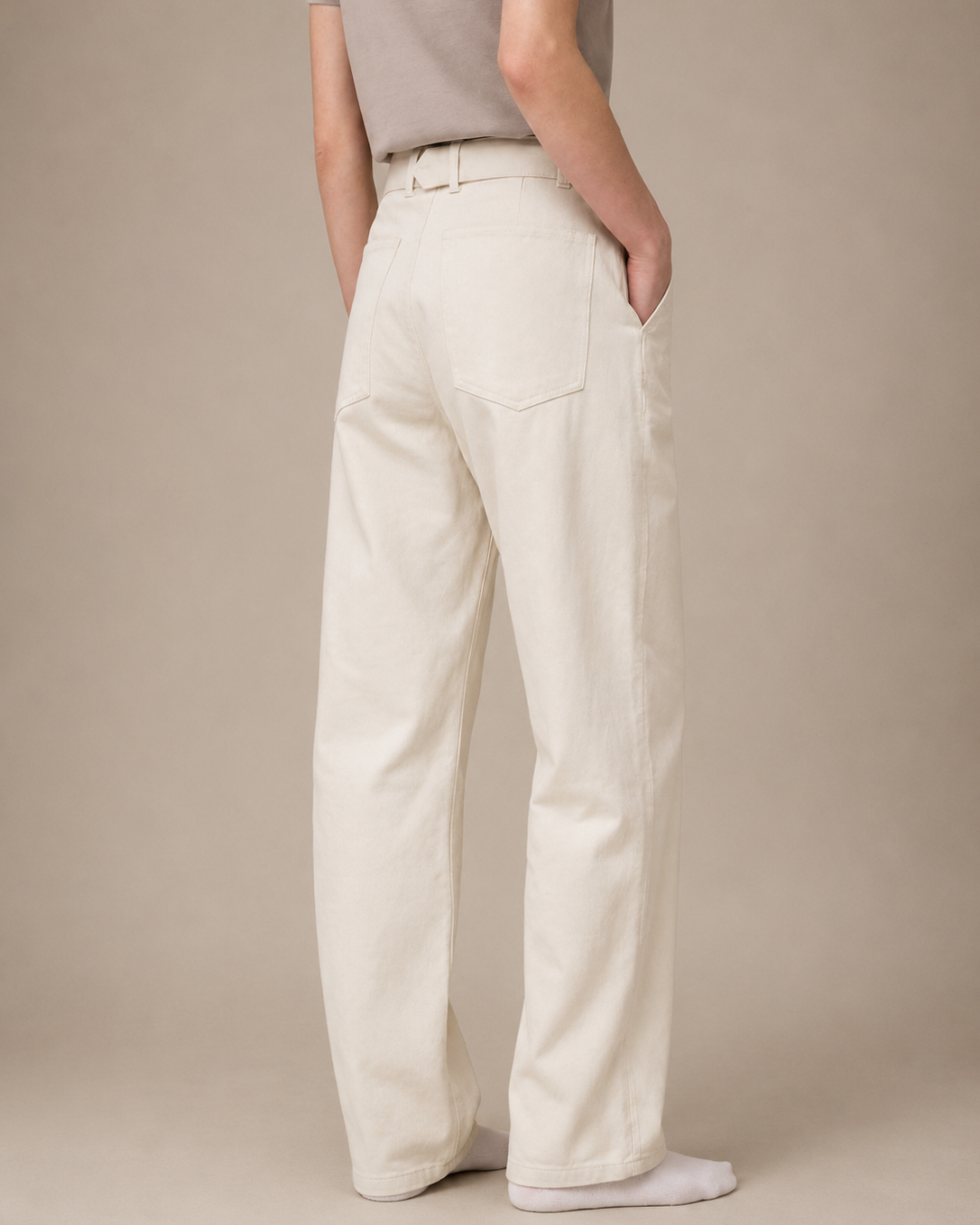 Person wearing white pants against a beige background