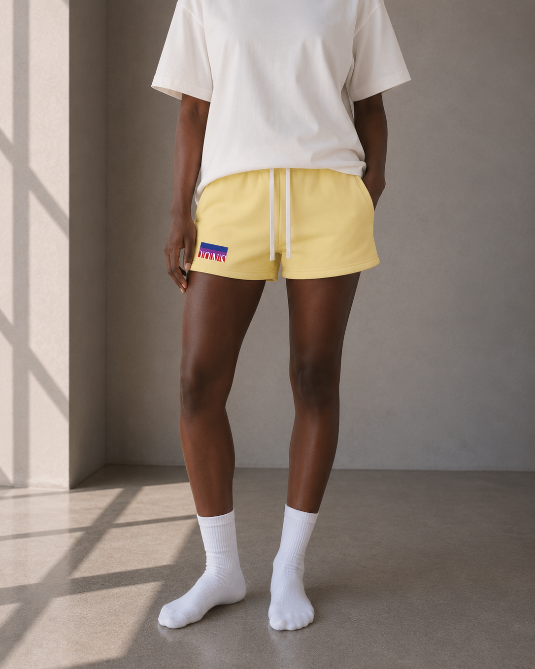 Person wearing yellow shorts with a visible brand logo against a neutral background