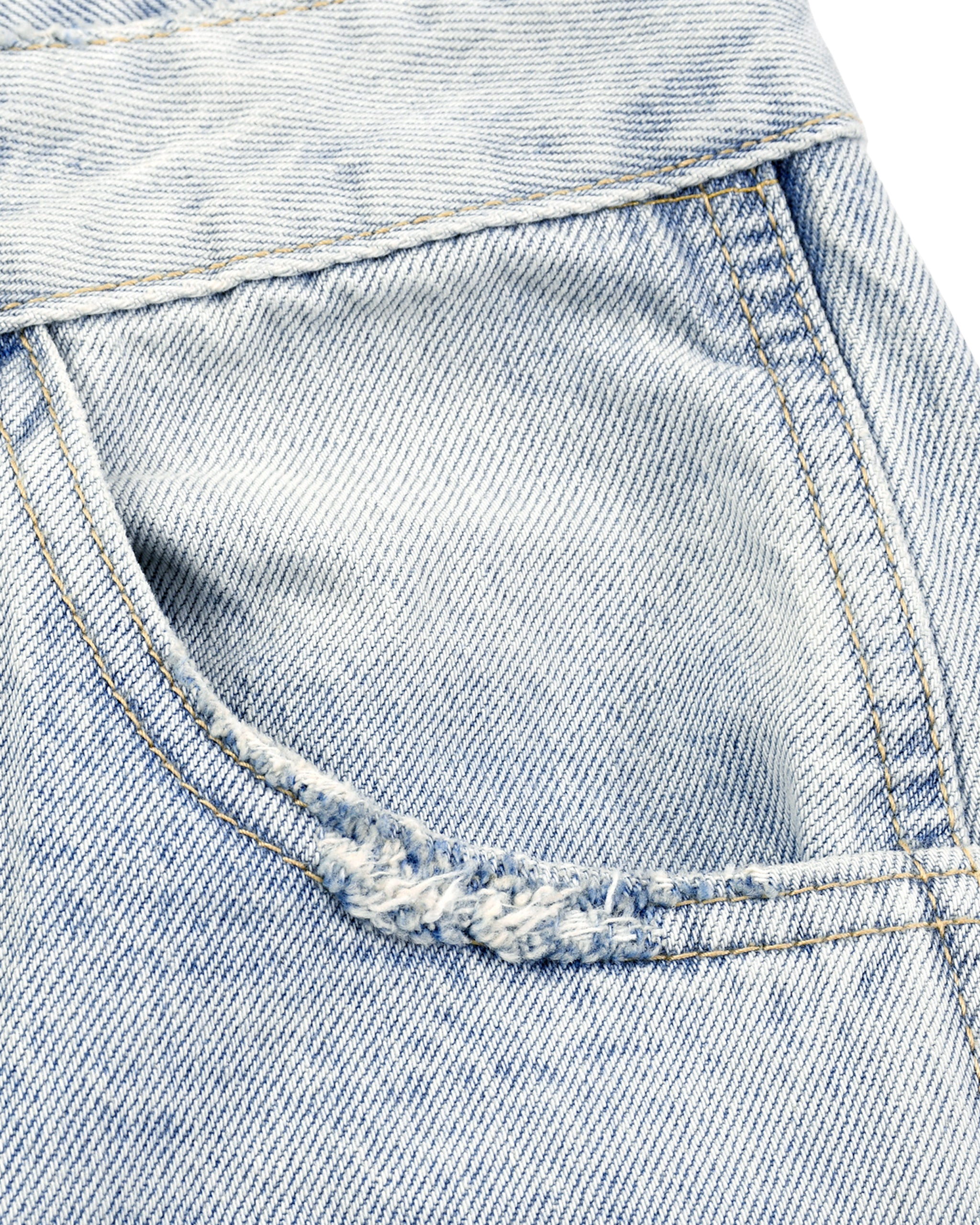 Close-up of a blue denim fabric with stitching details on a white background